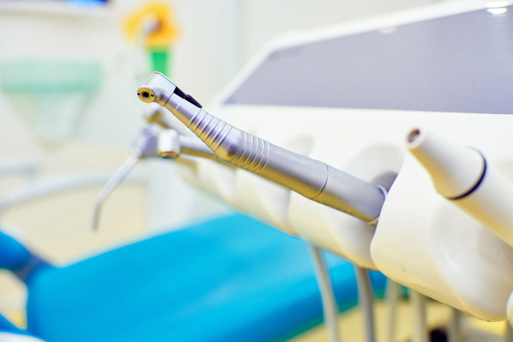 A close-up of dental instruments on a holder in a dental office, with a blurred blue chair in the background - Dentist University Place WA A close-up of dental instruments on a holder in a dental office, with a blurred blue chair in the background - Dentist University Place WA